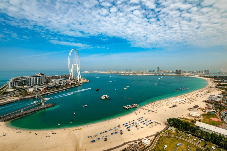Bãi biển JBR Dubai đông vui với nền cao ốc và vòng quay Ain Dubai